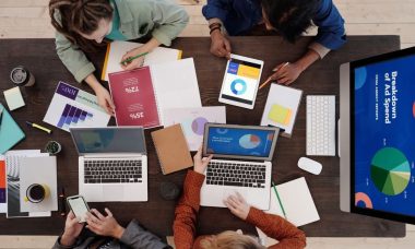 A diverse team collaborating on digital marketing strategies at a desk, using laptops and tablets.